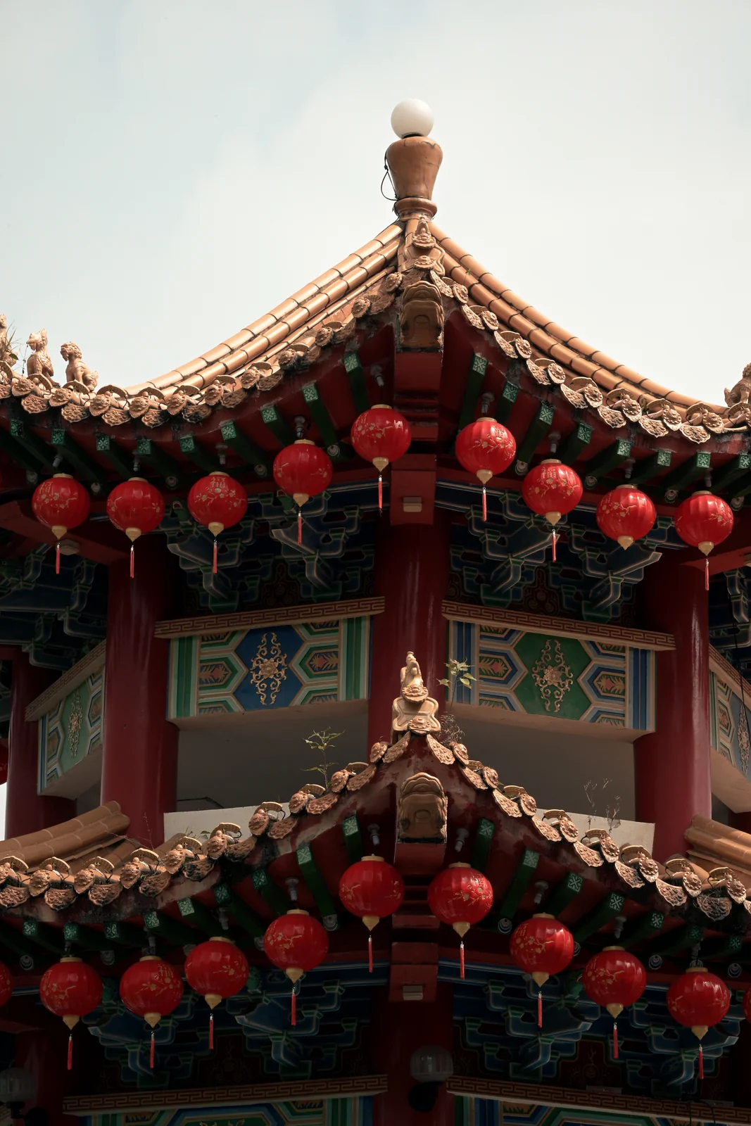Curved Chinese pagoda eaves and festive lantern strings against the sky
