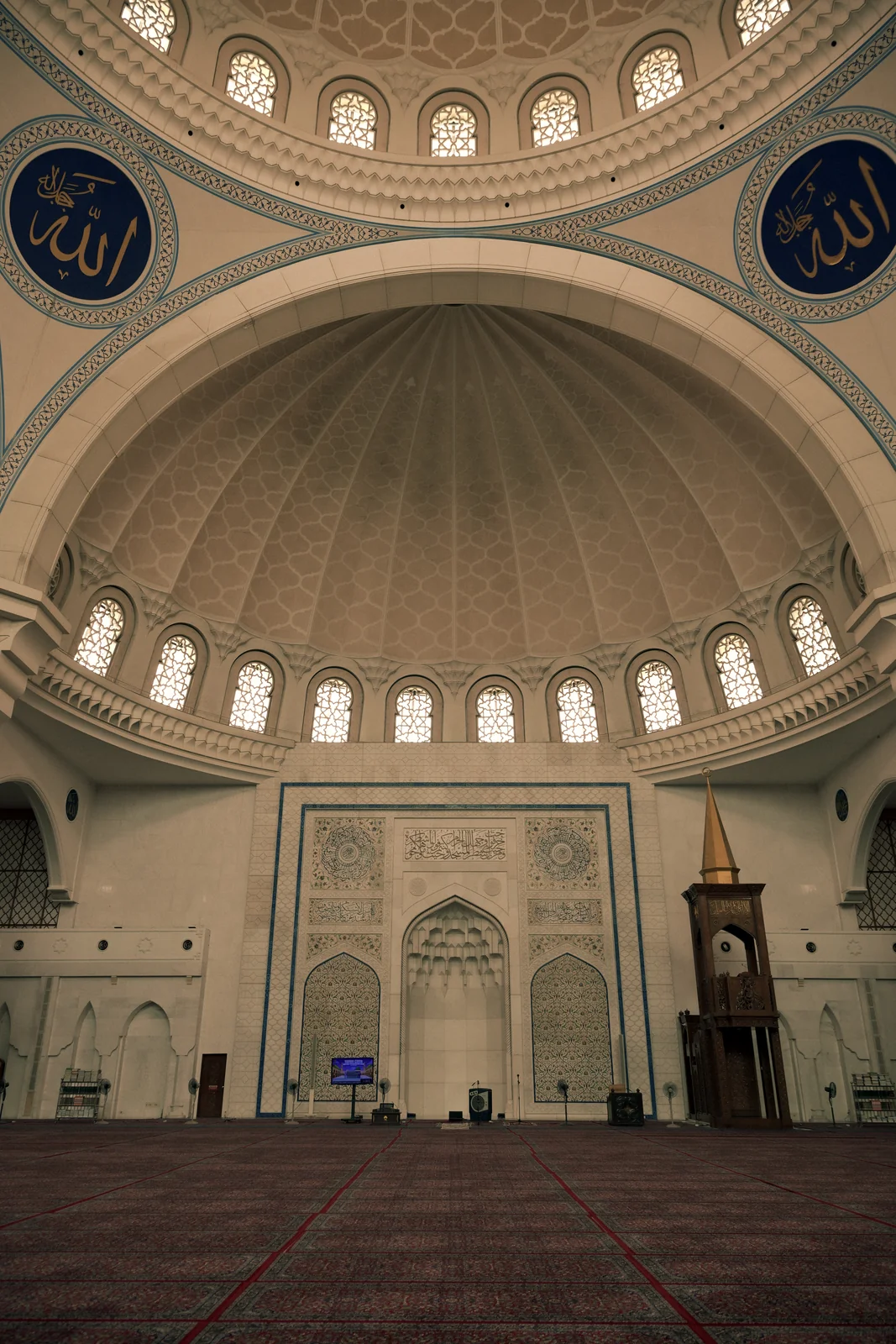 Grand prayer hall archways and sunlit stained-glass arched windows