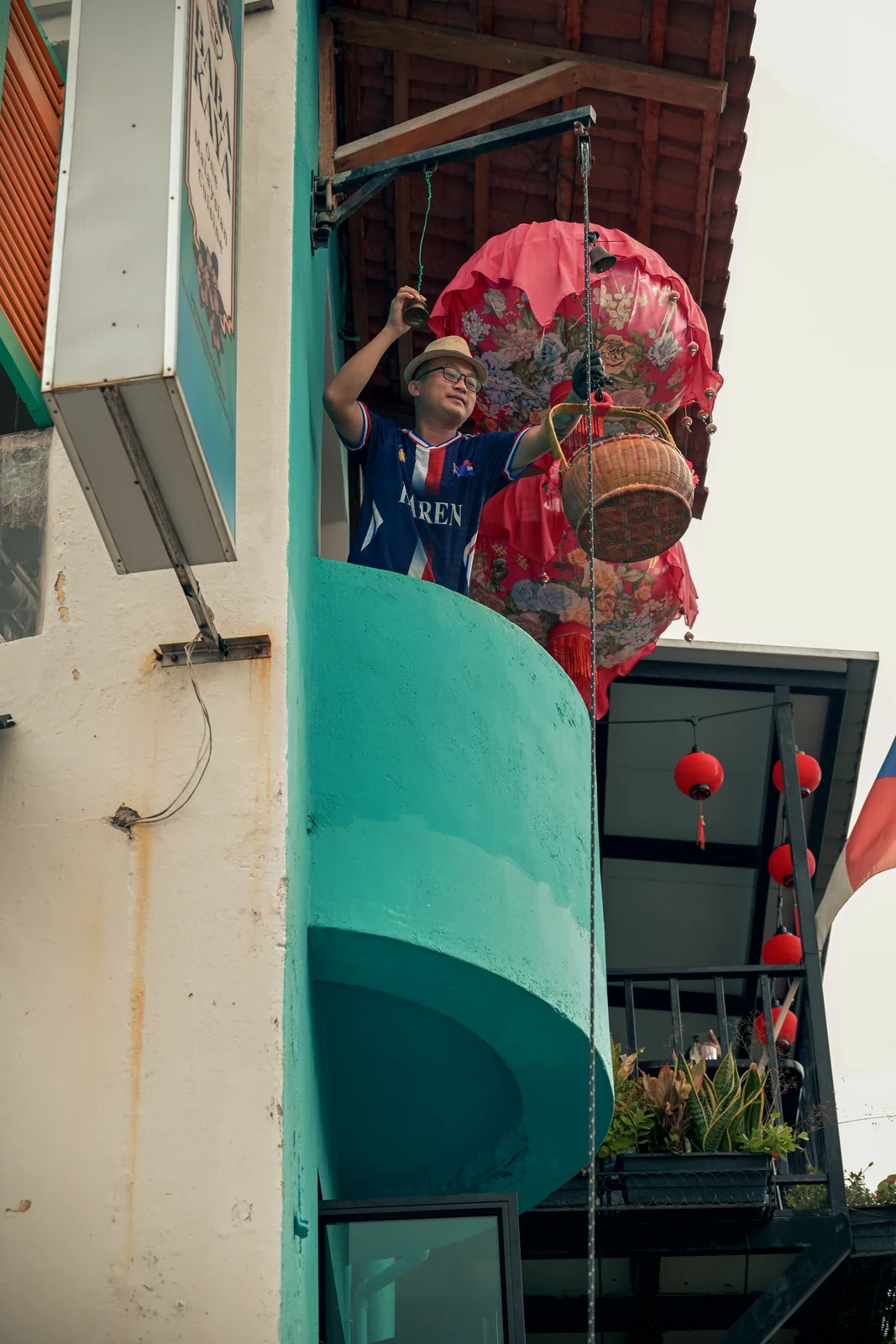 Vibrant painted heritage shophouse balcony with red hanging lanterns