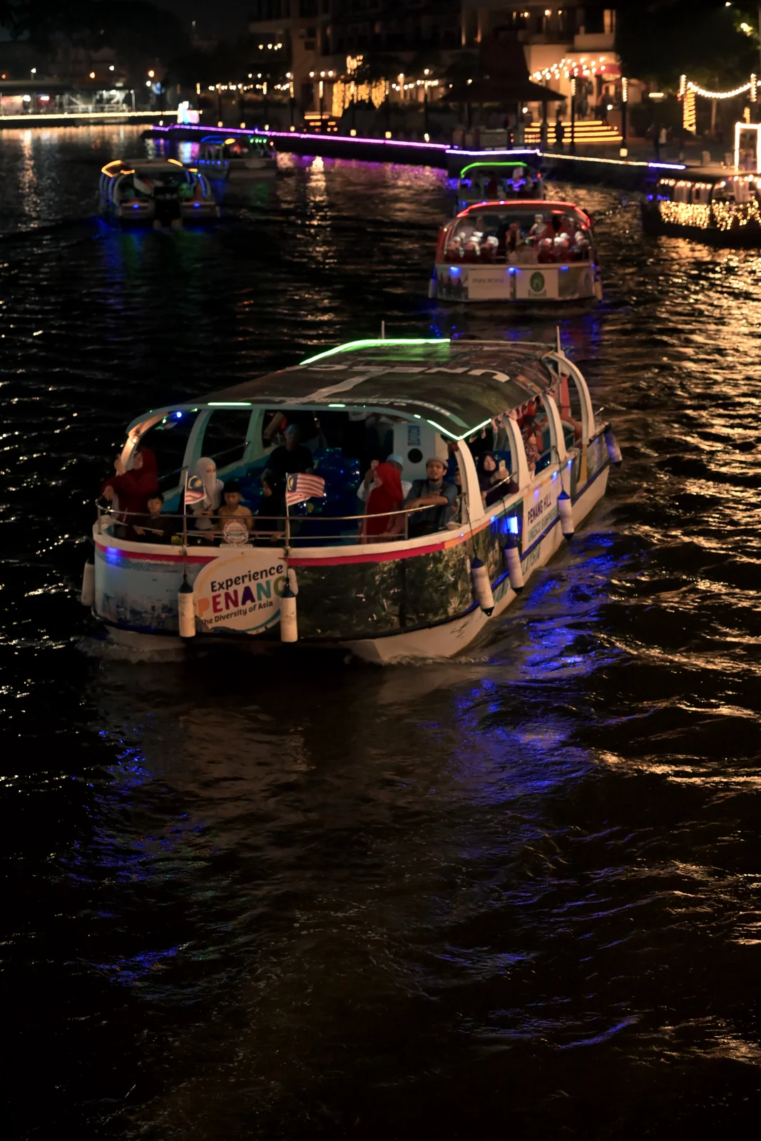 Malacca River Cruise boats sailing along neon-lit riverway at night