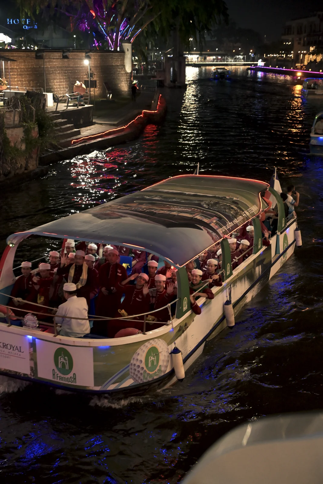 Travelers enjoying the night river breeze aboard the Malacca river cruise