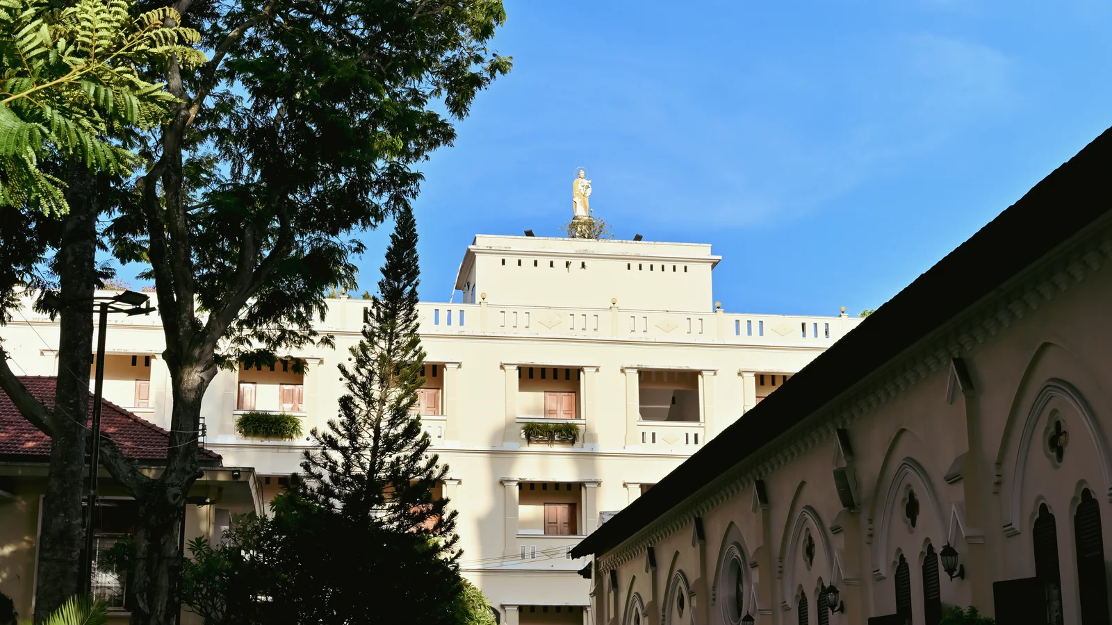 Diocesan pastoral building and arched architectural walkway under sunny blue sky
