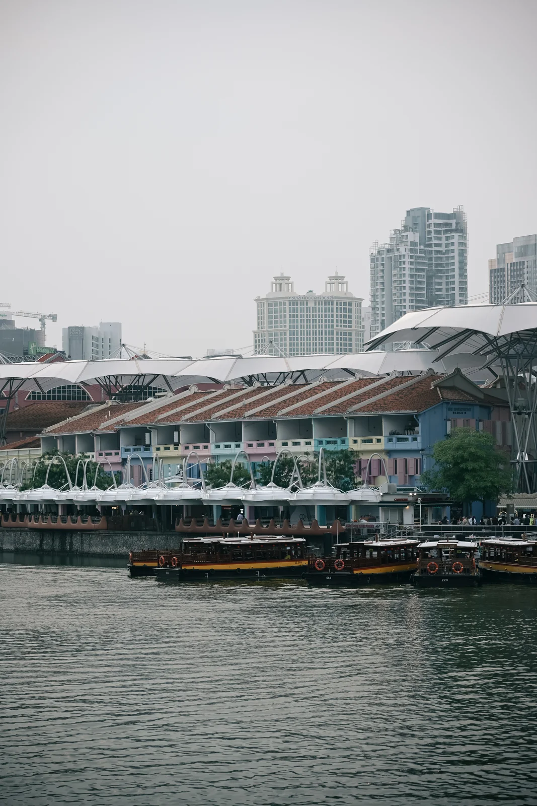 Bustling daytime river cruise passing vibrant Clarke Quay dining terraces
