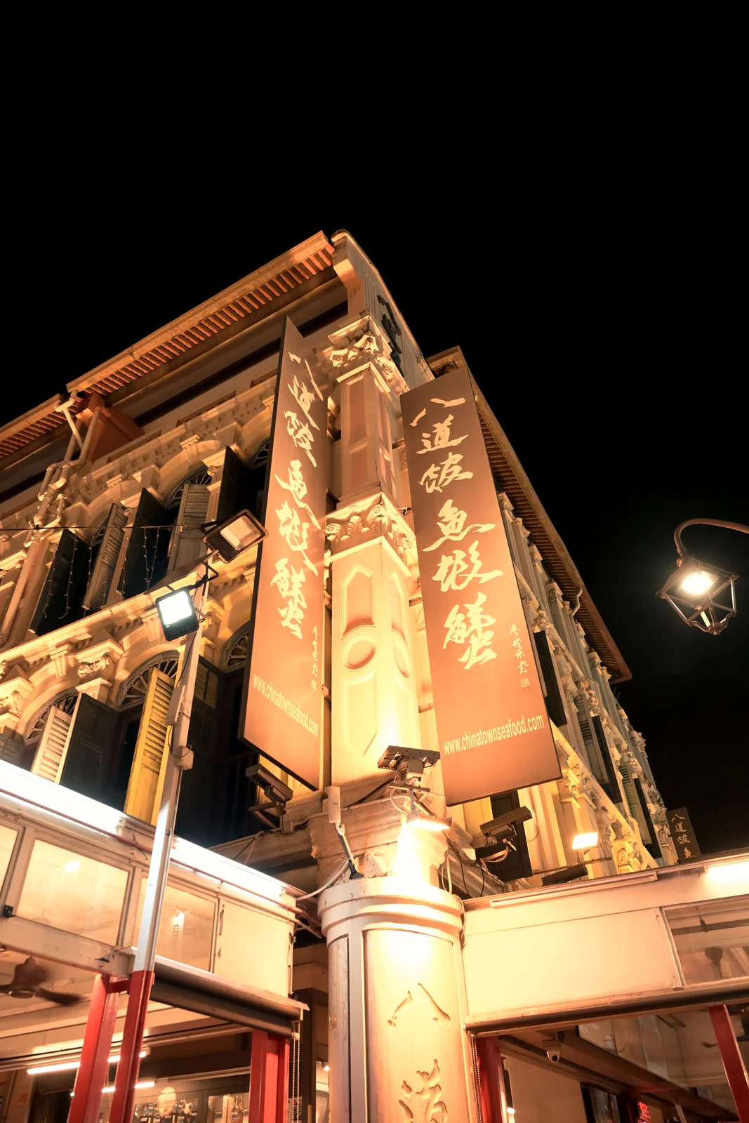 Historic Peranakan shophouse corner glowing under warm lantern light