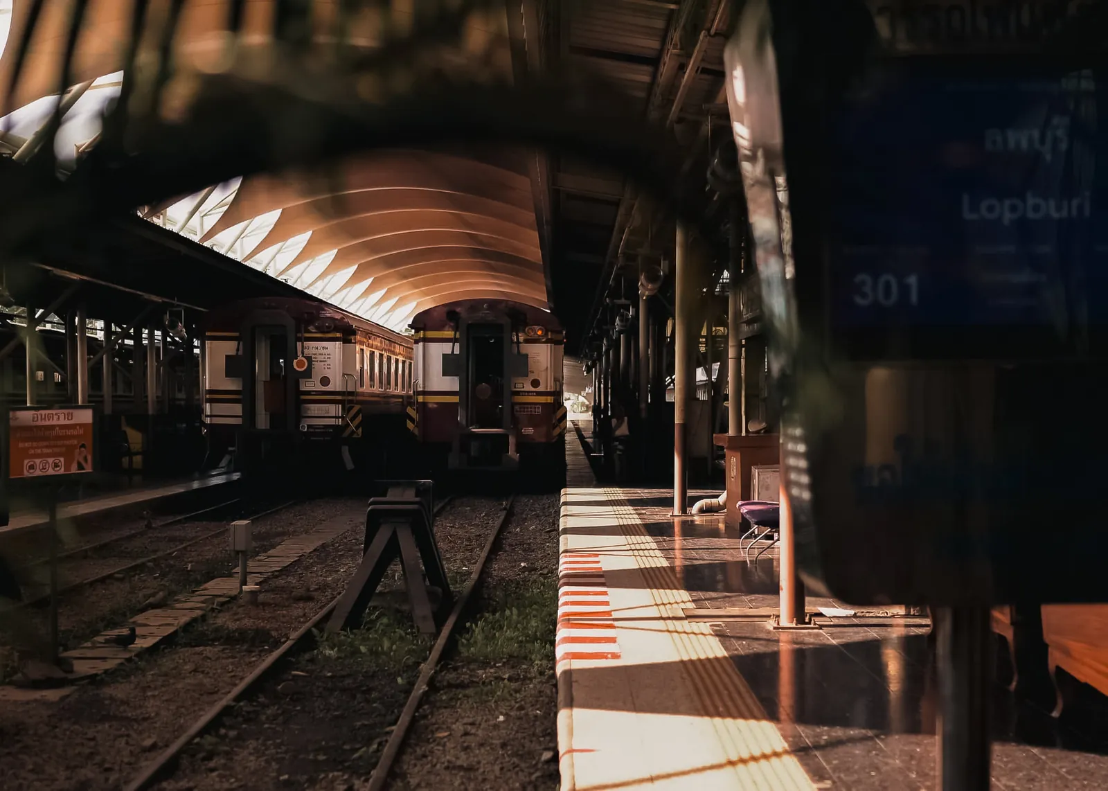 Vintage passenger trains stationed along sunlit railway platforms