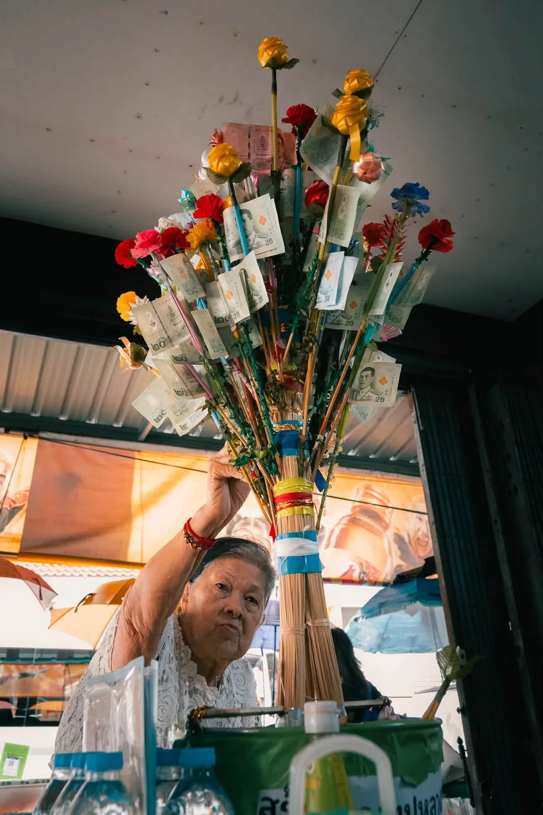 Elderly Thai vendor holding traditional Buddhist merit-making money tree