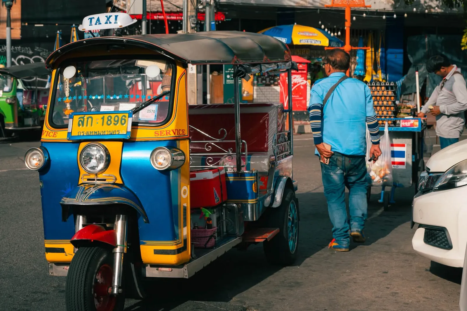 Tuk-Tuk taxi on a busy street with local driver walking alongside