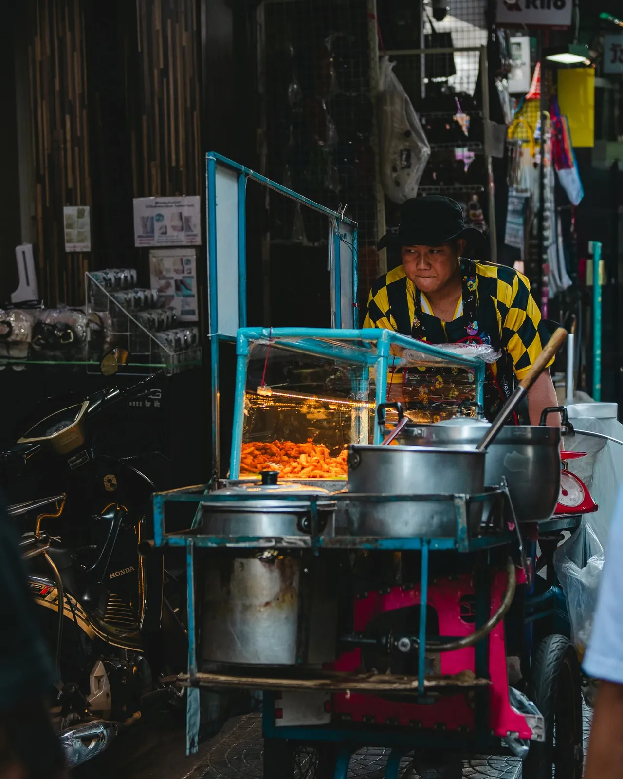 Street food chef pushing a mobile cart filled with hot broth and crispy delicacies